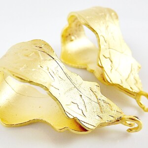 Puede incluir: Dos ba&uacute;les de colgante de metal dorado con un dise&ntilde;o de hoja. Cada ba&uacute;l tiene un bucle en la parte inferior para sujetar un colgante.