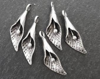 May include: Six silver metal flower charms with a textured surface. Each charm features a stylized flower with a rounded center.
