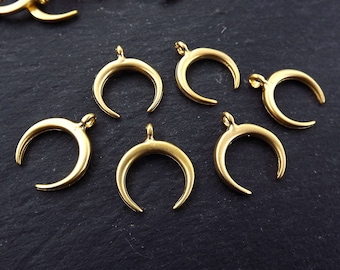 May include: A set of seven gold crescent moon charms. The charms are made of metal and have a smooth, polished finish.