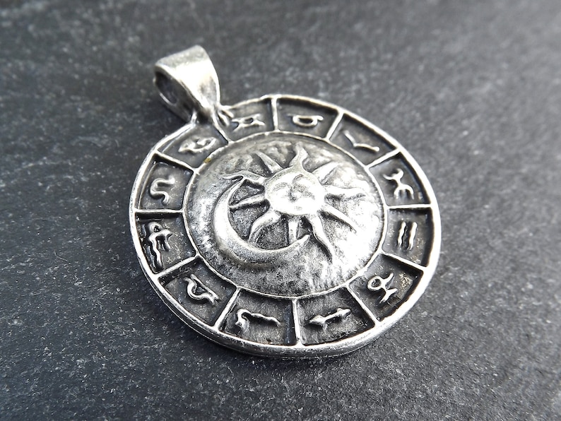 May include: Silver pendant featuring a sun and moon design with the zodiac symbols around the edge.