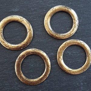 May include: Four gold-toned metal rings with a textured surface. The rings are approximately 2 inches in diameter.