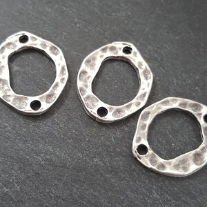 May include: Three silver-toned metal connector charms with a hammered texture and a round opening. Each charm has two holes for attaching jewelry.