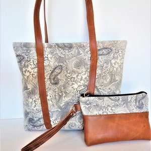 Sueded paisley leather shoulder bag in grays and ivory with wristlet.   Leather shoulder bag and wristlet in ivory and black paisley.