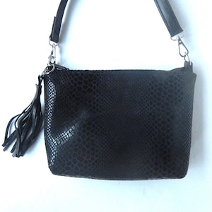 May include: A black leather handbag with a snakeskin pattern and a tassel. The bag has a long strap and a silver clasp.