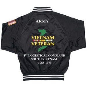 May include: Black satin bomber jacket with white stripes on the collar and cuffs. The back of the jacket features an embroidered green map of Vietnam with the text "Vietnam Veteran" and "1st Logistical Command South Vietnam 1965-1970". The jacket also has a small American flag patch on the left sleeve.