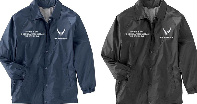 May include: Two lightweight jackets with snap closures. The jacket on the left is navy blue and the jacket on the right is black. Both jackets have a white embroidered logo on the left chest that says "FLY-FIGHT-WIN MCCONNELL AIR FORCE BASE WICHITA KANSAS" and a white embroidered logo on the right chest that says "U.S. AIR FORCE".