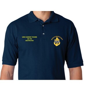 May include: A navy blue polo shirt with yellow embroidered text that reads "USS CASSIN YOUNG DD-793 DESTROYER" and a yellow embroidered anchor with the text "WORLD'S GREATEST NAVY USN".