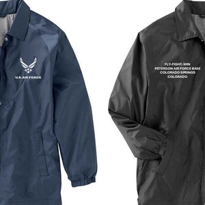May include: Two baseball jackets, one navy blue and one black, with the text "FLY FIGHT WIN" and "PETERSON AIR FORCE BASE" and "COLORADO SPRINGS" and "COLORADO" and "U.S. AIR FORCE" embroidered on the front.