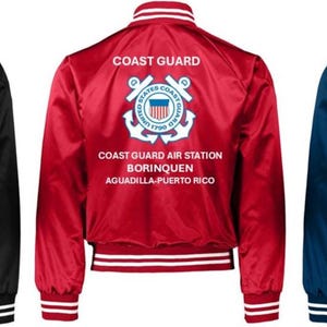 Puede incluir: Tres chaquetas bomber de sat&eacute;n en negro, rojo y azul marino. Cada chaqueta tiene pu&ntilde;os, cuello y dobladillo a rayas blancas. La parte posterior de cada chaqueta muestra las palabras "COAST GUARD" sobre un emblema de la Guardia Costera y el texto "COAST GUARD AIR STATION BORINQUEN AGUADILLA-PUERTO RICO."