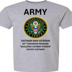 May include: A gray t-shirt with a black print of the United States Army seal and the text "ARMY", "VIETNAM WAR VETERAN", "20TH ENGINEER BRIGADE", "BUILDING COMBAT POWER", and "SOUTH VIETNAM".