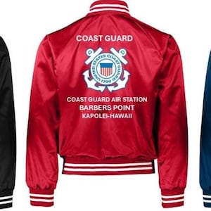 Puede incluir: Tres chaquetas bomber de sat&eacute;n en negro, rojo y azul marino. Cada chaqueta tiene pu&ntilde;os, cuello y dobladillo a rayas blancas. La parte trasera de cada chaqueta muestra las palabras "COAST GUARD" sobre un emblema de la Guardia Costera y el texto "COAST GUARD AIR STATION BARBERS POINT KAPOLEI-HAWAII."