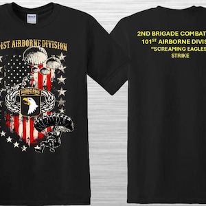 May include: Black t-shirt featuring the 101st Airborne Division emblem with an American flag design, parachutes, and the text "101st Airborne Division." The back of the shirt displays text: "2nd Brigade Combat Team, 101st Airborne Division, 'Screaming Eagles,' Strike."