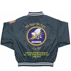 May include: A dark blue bomber jacket with a white and black striped collar and cuffs. The back of the jacket features a yellow and purple embroidered patch with a bee and the text "SEABEES" and "Can Do". The jacket also has the text "We Build" "We Fight" and "VIETNAM WAR VETERAN "ALL GAVE SOME, SOME GAVE ALL" 1959-1975" embroidered on the back.