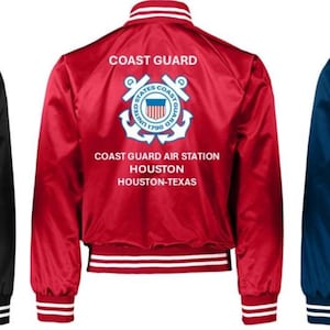 Puede incluir: Tres chaquetas bomber de sat&eacute;n en negro, rojo y azul marino. Cada chaqueta presenta ribetes blancos y azules, un cuello blanco y las palabras "COAST GUARD" sobre un emblema de la Guardia Costera. Debajo, se lee "COAST GUARD AIR STATION HOUSTON HOUSTON-TEXAS."