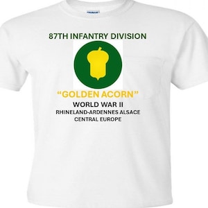 Può includere: Maglietta bianca con una tasca verde che presenta una ghianda gialla e il testo "87th Infantry Division", "Golden Acorn", "World War II", "Rhineland-Ardennes Alsace" e "Central Europe".