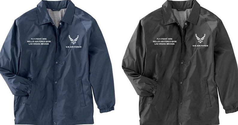 May include: Two jackets, one navy blue and one black, with a white embroidered logo and text that reads "FLY-FIGHT-WIN NELLIS AIR FORCE BASE LAS VEGAS-NEVADA" and "U.S. AIR FORCE".