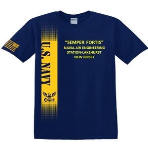 May include: A navy blue t-shirt with a yellow vertical stripe featuring the words "U.S. NAVY" and a stylised eagle with a cross. The stripe also has a repeating pattern of small squares. The text "SEMPER FORTIS" is printed in yellow on the front of the shirt, along with the words "NAVAL AIR ENGINEERING STATION-LAKEHURST NEW JERSEY".