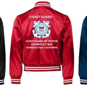 Puede incluir: Tres chaquetas bomber de sat&eacute;n en negro, rojo y azul marino. Cada chaqueta tiene pu&ntilde;os, cuello y dobladillo a rayas blancas. La parte posterior de cada chaqueta muestra el texto "COAST GUARD" sobre un emblema de la Guardia Costera y el texto "COAST GUARD AIR STATION HUMBOLDT BAY-CALIFORNIA."