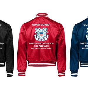 May include: Three satin bomber jackets in black, red, and navy blue. Each jacket features the words "Coast Guard" above a crest and text that reads "Coast Guard Air Station Los Angeles Los Angeles-California". The jackets have white and black striped cuffs and collars.