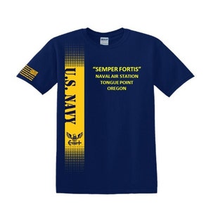Pode incluir: Uma camiseta azul marinho com uma faixa amarela ao lado. A faixa apresenta as palavras "U.S. Navy" e um pequeno emblema de águia. O texto "Semper Fortis" está impresso na camiseta, junto com "Naval Air Station Tongue Point Oregon."