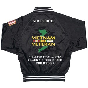 May include: Black bomber jacket with white stripes on the collar and cuffs. The back of the jacket features an embroidered map of Vietnam with the text "Vietnam Veteran" and "Thunder From Above" Clark Air Force Base Philippines.