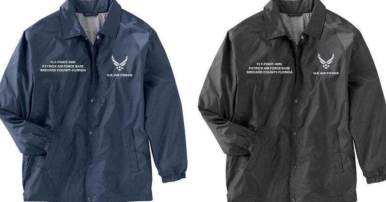 May include: Two jackets, one navy blue and one black, with a white embroidered logo and text that reads "FLY-FIGHT WIN PATRICK AIR FORCE BASE BREVARD COUNTY FLORIDA US AIR FORCE".
