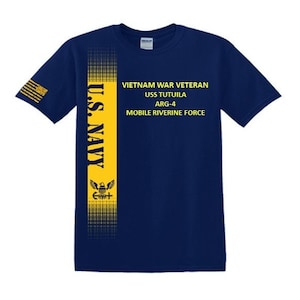 May include: Navy blue t-shirt with yellow vertical stripe and text. The stripe features the words "U.S. NAVY" and a crest. The shirt also displays "VIETNAM WAR VETERAN USS TUTUILA ARG-4 MOBILE RIVERINE FORCE" in yellow.
