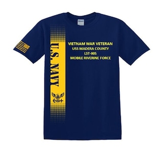 Könnte beinhalten: Ein marineblaues T-Shirt mit einem gelben Streifen auf der linken Seite. Der Streifen zeigt die Worte "U.S. NAVY" und einen stilisierten Adler mit einem Schild. Der Text auf dem T-Shirt lautet "VIETNAM WAR VETERAN USS MADERA COUNTY LST-905 MOBILE RIVERINE FORCE".
