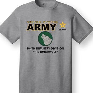 May include: A gray t-shirt with the text "UNITED STATES ARMY" and a yellow star. Below the text is a green circle with a white wolf howling. The text "104TH INFANTRY DIVISION" and "THE TIMBERWOLF" are below the circle.