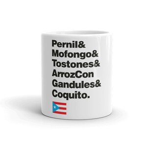Pode incluir: Caneca de cerâmica branca com texto preto que diz "Pernil & Mofongo & Tostones & ArrozCon Gandules & Coquito." A caneca também apresenta uma pequena imagem da bandeira porto-riquenha.