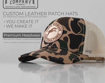 May include: A camouflage pattern hat with a leather patch that reads "Cape Romain Contractors." The hat has a mesh back and a curved brim. The text "PG Hat Company" is visible in the upper left corner.