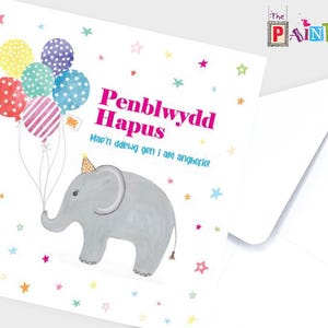 Puede incluir: Una tarjeta blanca con un elefante rosa sosteniendo globos de colores. La tarjeta dice "Penblwydd Hapus" y "Have a day you will always remember!" en letras rosas.