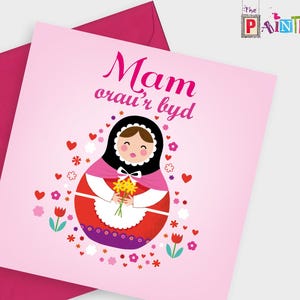 May include: Pink card with a cartoon illustration of a Russian nesting doll holding flowers. The text on the card reads "Mam orau'r byd".