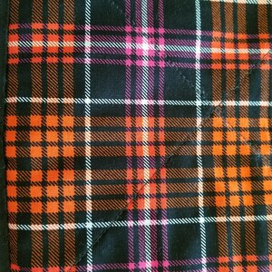 May include: Orange, black, white, and pink plaid fabric with a diagonal seam.