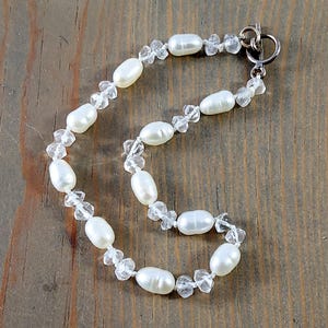 May include: A white pearl and crystal necklace with a silver clasp.