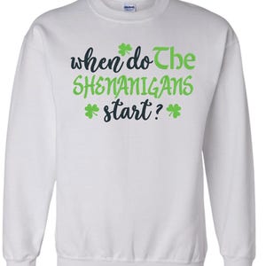 May include: White sweatshirt with green shamrocks and the text "when do the shenanigans start?"