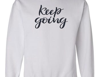 May include: White sweatshirt with the text "keep going" in black script lettering.