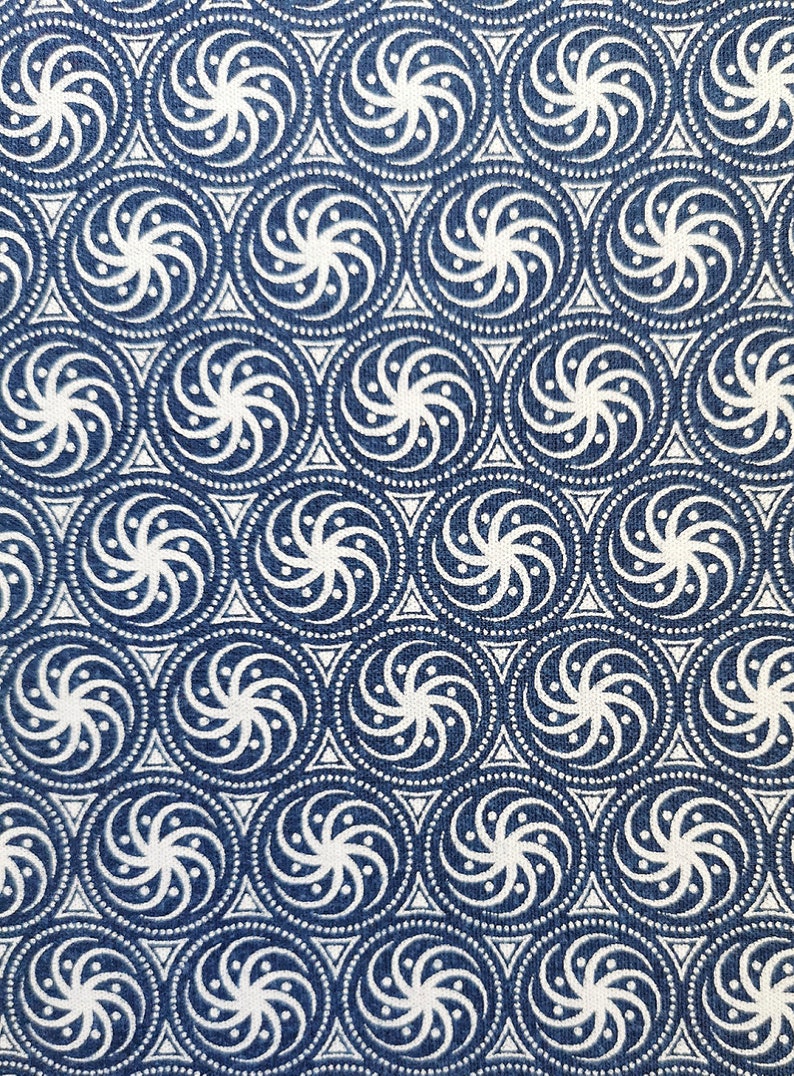 May include: A blue fabric with a white repeating pattern of swirling circles and dots.