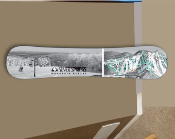 Może przedstawiać: Czarno-biały snowboard z fotografią śnieżnego krajobrazu górskiego i mapą ośrodka narciarskiego. Snowboard ma nadrukowany napis "Seven Springs Mountain Resort".
