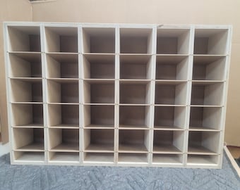Könnte beinhalten: Ein Holzregal mit 24 einzelnen Fächern. Das Regal ist aus hellbraunem Holz gefertigt und hat ein schlichtes, minimalistisches Design.