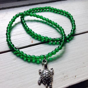 May include: A green beaded necklace with a silver turtle charm.