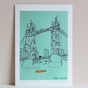 May include: A black and white line drawing of Tower Bridge in London, England. The bridge is drawn in a simple style with a turquoise background. The text "Tower Bridge London" and "Line Drawn" is written below the bridge.