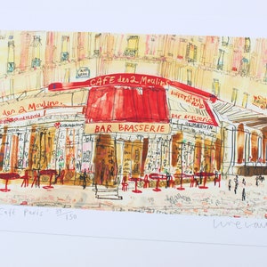 May include: Watercolor print of the Cafe des 2 Moulins in Paris, with a red awning and outdoor seating. The artwork features the text "CAFE des 2 Moulins" and "BAR BRASSERIE". The print is numbered 39/150 and signed.