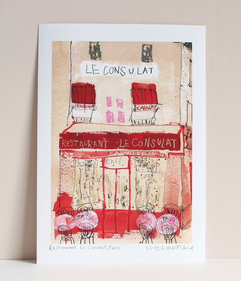 May include: A watercolor illustration of a Parisian cafe called "Restaurant Le Consulat" with red awnings and a cafe sign. The cafe is depicted with a red facade and windows with handwritten notes. The illustration is signed "Live Launeid" in the bottom right corner.
