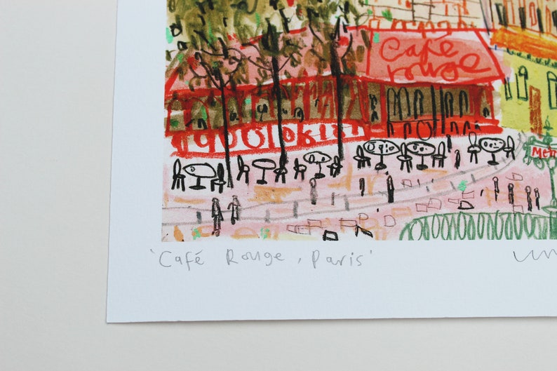 May include: A colorful illustration of a cafe in Paris, France. The cafe is called "Cafe Rouge" and is depicted with red, green, and yellow colors. The illustration is drawn in a childlike style with simple lines and shapes.