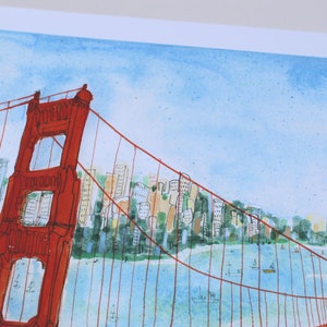 May include: A watercolor painting of the Golden Gate Bridge in vibrant red ink lines against a light blue sky. The background features a stylized cityscape with multi-colored buildings and green trees along the shoreline, with small boats on the water.