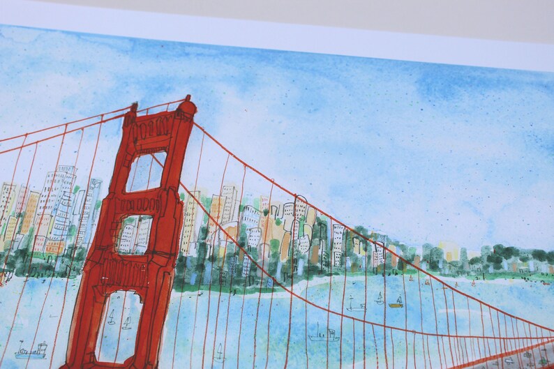 May include: A watercolor painting of the Golden Gate Bridge in vibrant red ink lines against a light blue sky. The background features a stylized cityscape with multi-colored buildings and green trees along the shoreline, with small boats on the water.