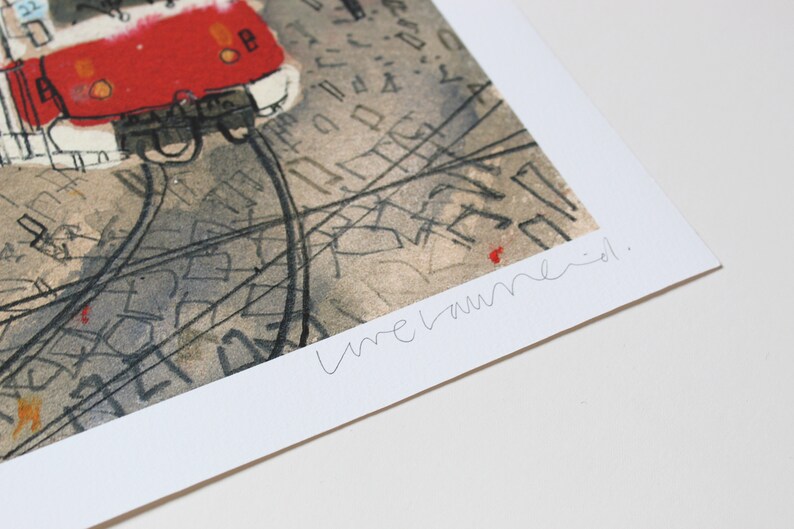 May include: A black and white print of a red tram with a handwritten signature that says "une laune."