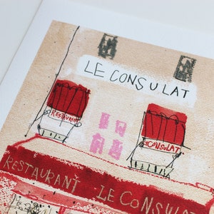 May include: A watercolor illustration of a building with the text "LE CONSULAT" written above the entrance. The building has two windows with red awnings and the text "RESTAURANT" written on one of the awnings. The building is painted in a light brown color.
