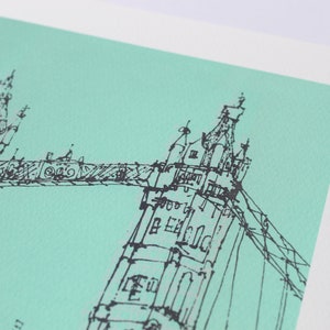 May include: A black and white line drawing of the Tower Bridge in London, against a light turquoise background.